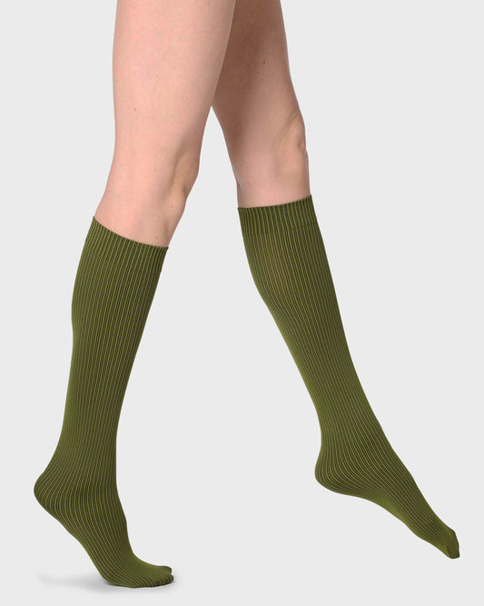 A pair of ribbed knee-high socks in olive green, shown on a model's legs against a light gray background.