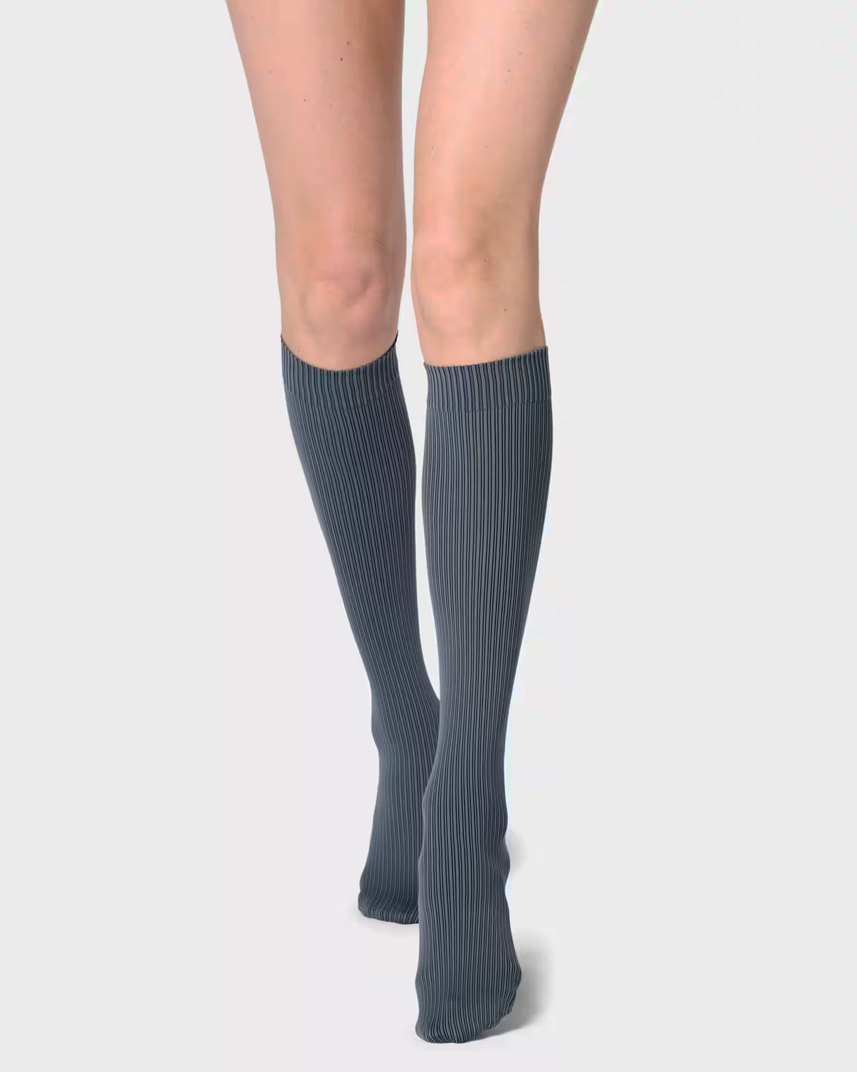 A pair of ribbed knee-high socks in a dark slate gray color, worn by a model against a light gray studio background.