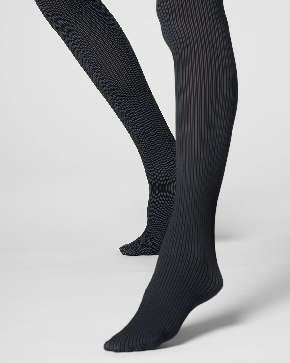 Grey ribbed tights worn on legs, shown from the calves down against a light gray studio background.