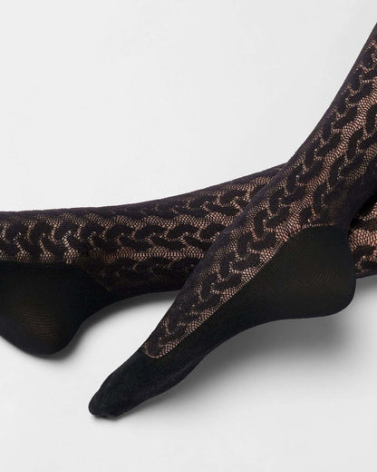 Black lace tights with a sheer chain-link pattern and solid black toe, heel, and sole sections, shown on feet against a light gray background.