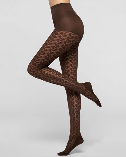 A model's legs wearing sheer brown tights with a repeating chevron pattern, shown against a light gray studio background.