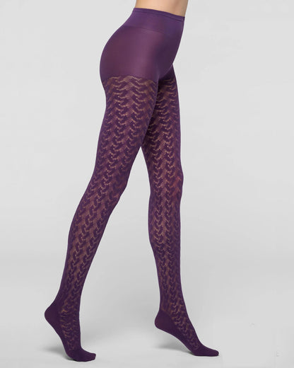 Purple patterned tights worn by a model, showing a high-waisted waistband and a textured chevron lace pattern on the legs, set against a plain light gray studio background.