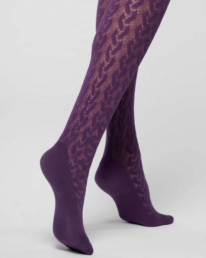 Purple cable knit patterned tights worn on legs, shown from the ankle up against a light gray studio background.