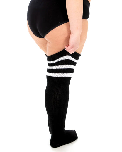 Thick, super-stretchy black knitted thigh-high socks featuring a triple white sports-style striped cuff and a slimmer, more comfortable foot. Back view.