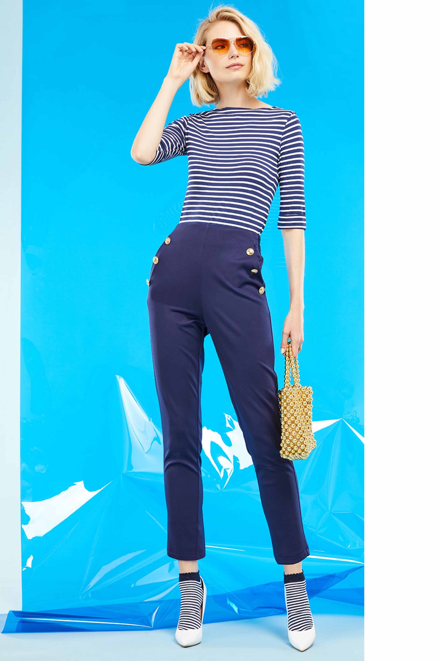SiSi Brigitte Trouser - High waisted navy blue trouser leggings with elasticated waist band on the back, side pockets and big gold button details along the pockets. Worn with a stripe top, low ankle socks and white high heels..