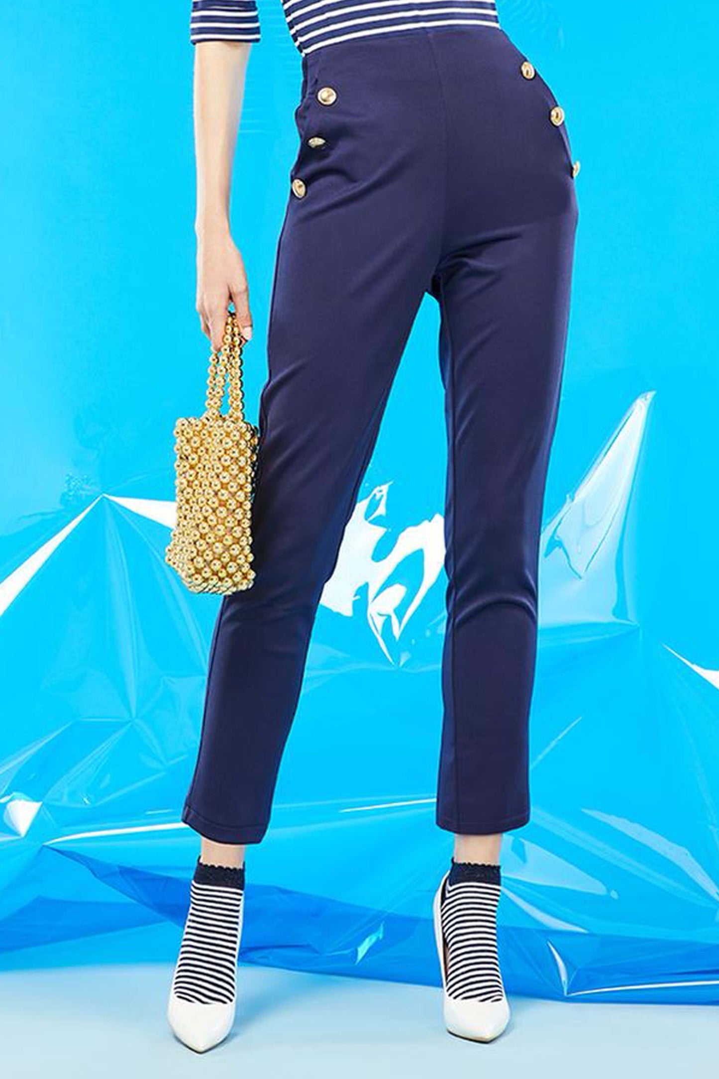 SiSi Brigitte Trouser - High waisted navy blue trouser leggings with elasticated waist band on the back, side pockets and big gold button details along the pockets. Worn with a stripe top, low ankle socks and white high heels.