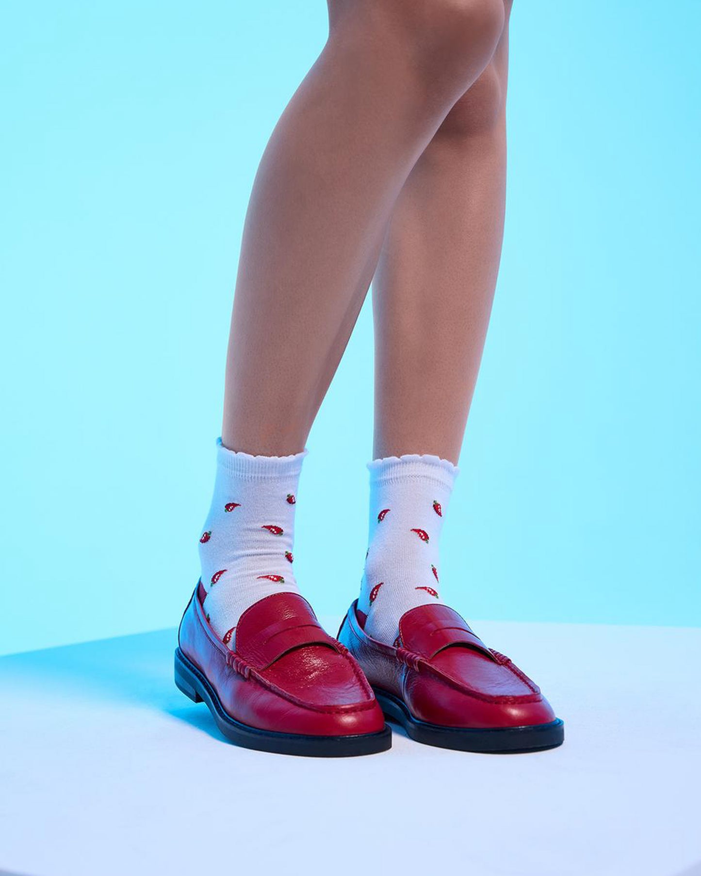 Red loafers and white socks with red patterns on a light blue background