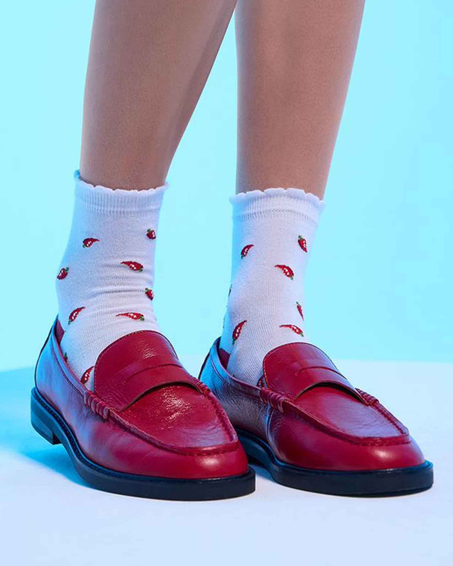 Red loafers with white socks featuring red patterns on a blue background