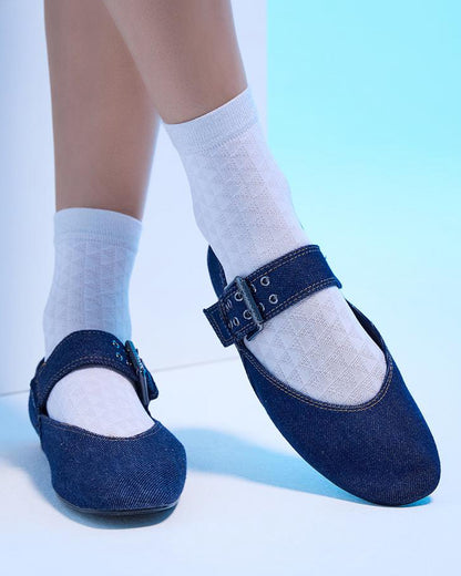 Blue shoes with buckles worn with white socks on a light blue background