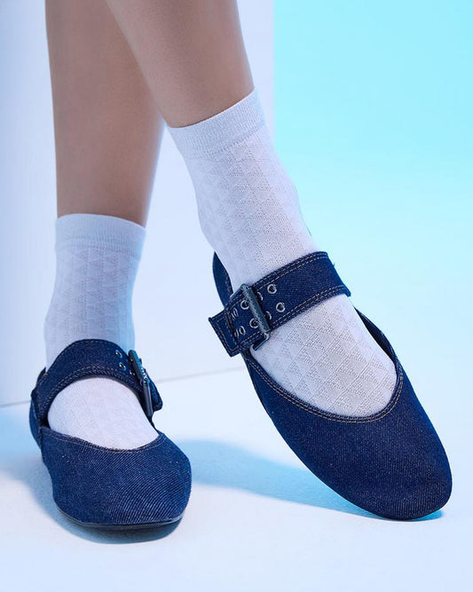 Blue shoes with buckles worn with white socks on a light blue background