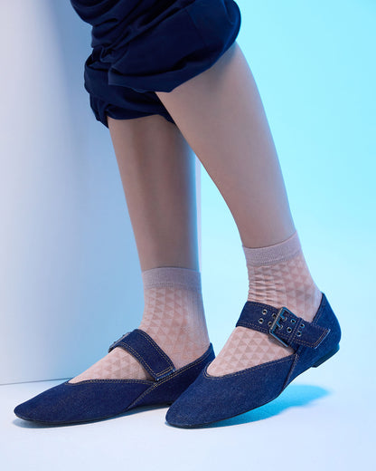 Navy flats worn with sheer socks on a light blue background