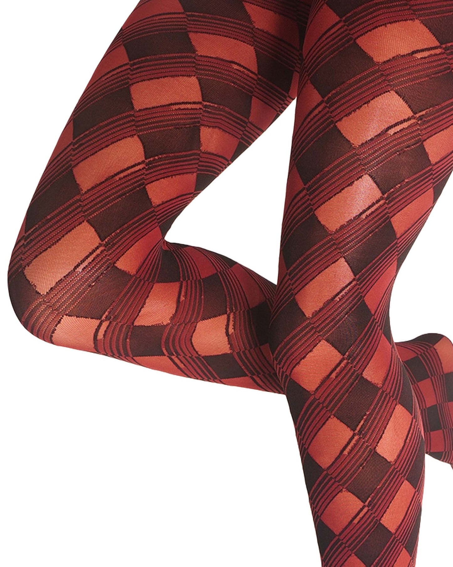 A close-up of a person's legs wearing patterned tights with a red, and black harlequin diamond design on a white background.