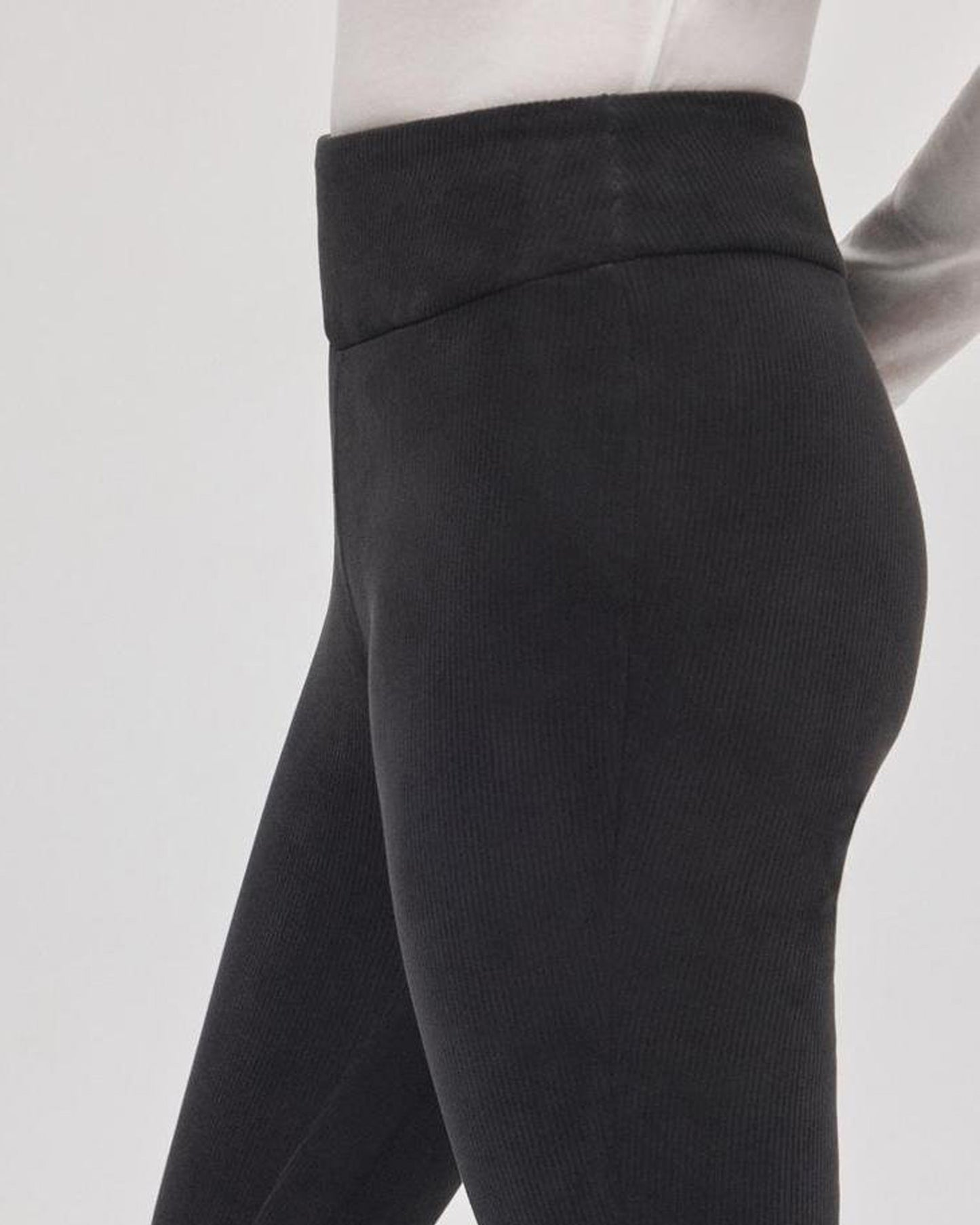 Black corduroy leggings on a model against a white background