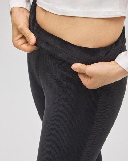 Person wearing black fleece lined cord pants with a white shirt on a light gray background